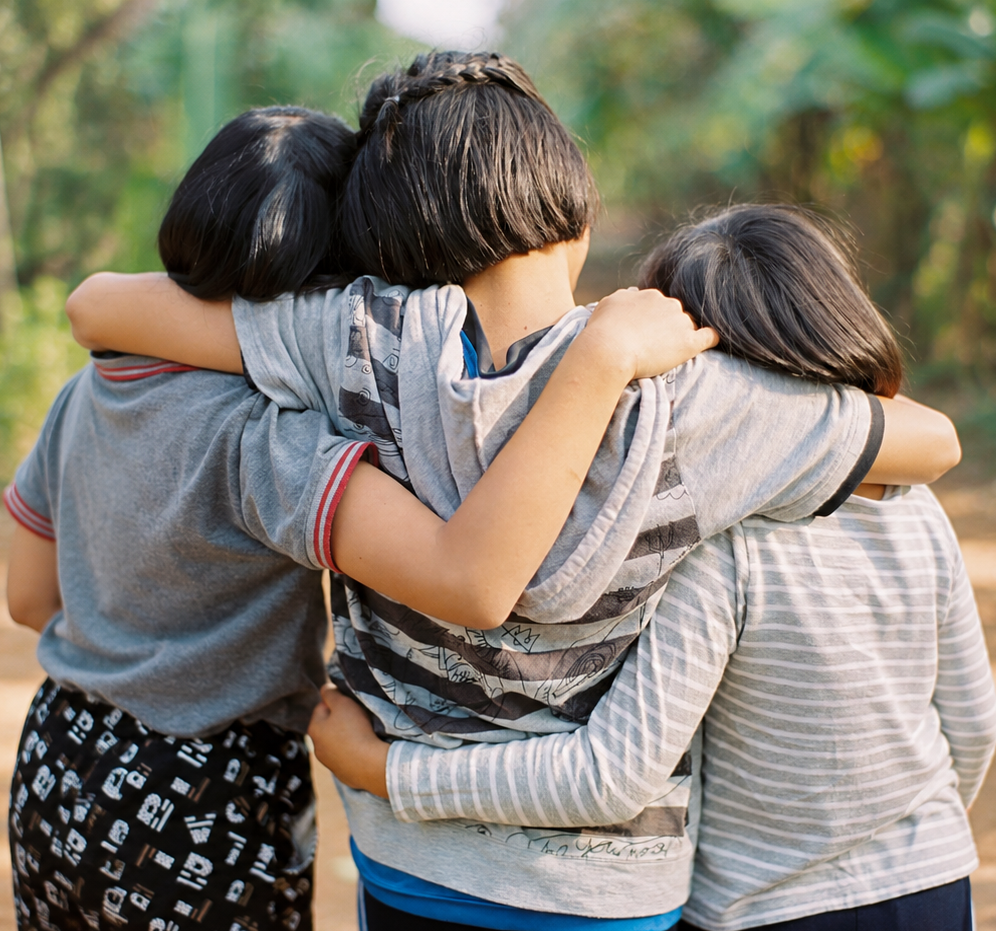 Children standing together with arms around one another